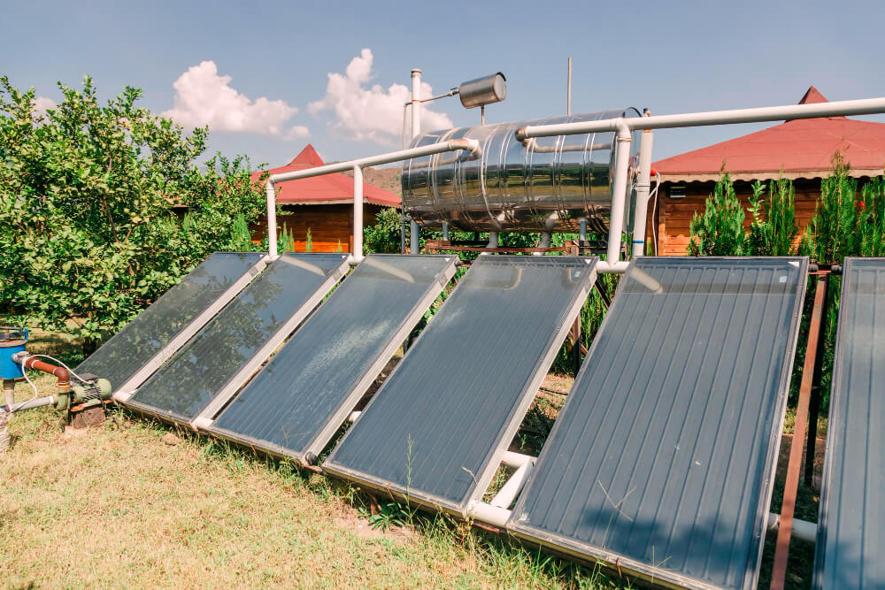 fuenf Solar-Flachkollektoren als Bodeninstallation im sommerlichen Garten